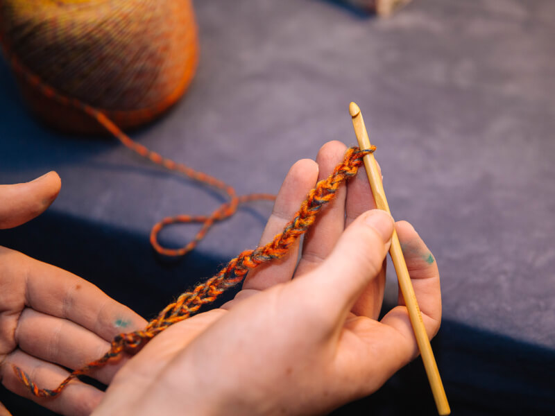 Hands holding a line of crochet attached to hook